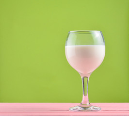A glass of fresh natural milk on a green background. Copy space..