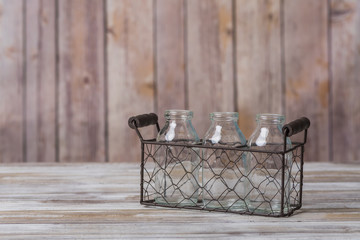 Obraz premium Old milk bottles in carrier with wood background