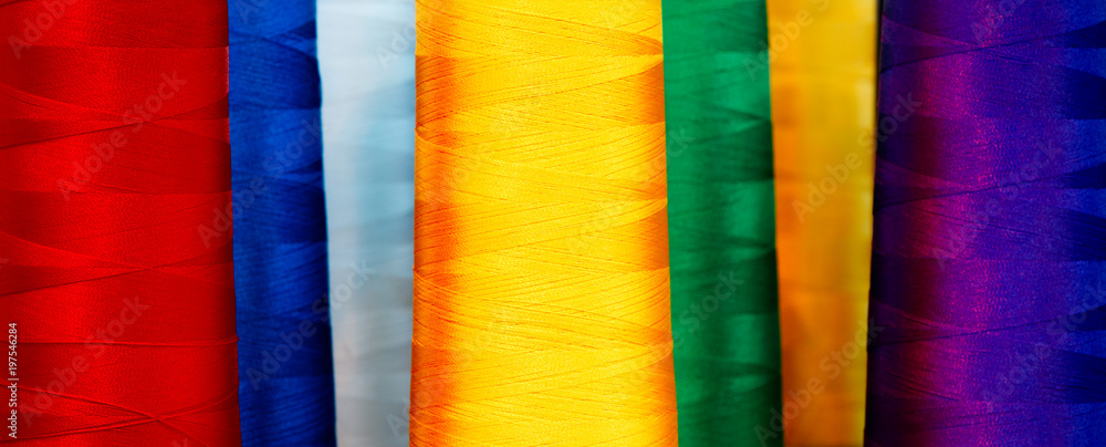 Poster bobbins with multicolor thread for industrial textile machines. multicolor background