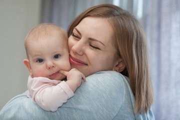 happy mom hugs a three-month-old baby
