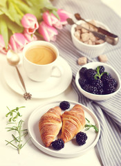 Morning breakfast with cup of coffee, croissants, fresh berries and pink flowers tulips on white tray, brown sugar, toned photo, sunlight, vintage