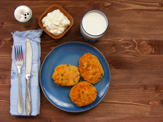 Rissoles of ham, cheese  and potatoes on blue plate, milk in glass, pepper-pot and sour cream in wooden bowl on rustic background with cover flat view with copy space