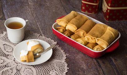 Pancakes stuffed with cottage cheese with sour cream and cup of tea. Breakfast. Sweet dessert of pancakes rolls.