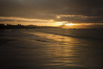 Obraz premium Sunset in 'Jurerê Internacional' beach. Golden light and colorful sky. Reflexes in the water. Florianópolis, Santa Catarina / Brazil