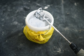 Drill paddle mixer on a bucket with white paint
