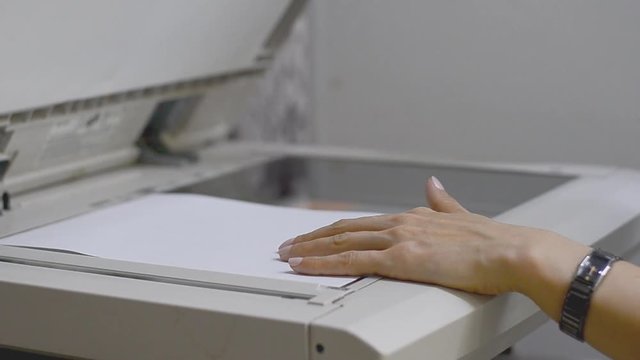 Girl in the office scans document in the copier