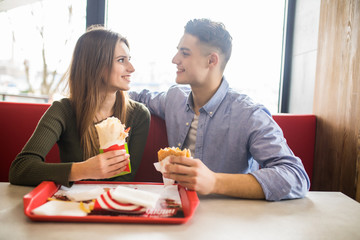 Cheerful Couple in eating burgers fast food Reastaurant