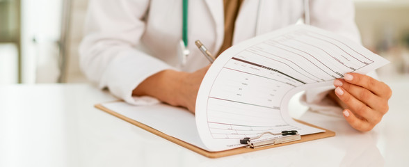 Closeup on medical doctor woman writing in clipboard