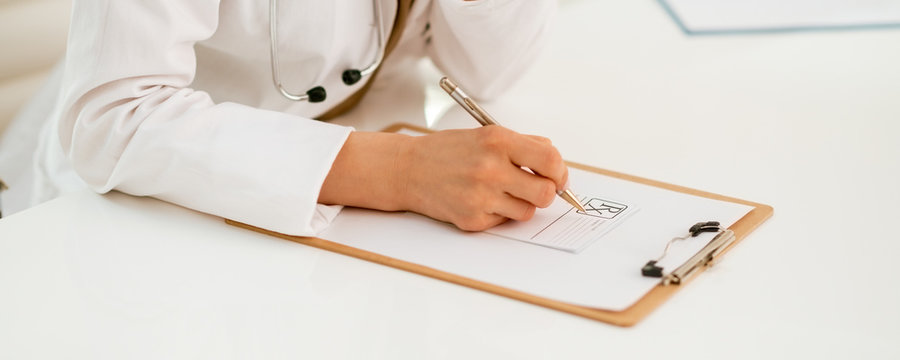 Closeup on medical doctor woman writing in clipboard