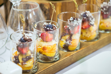 Candy bar closeup. Sweet Pieces of strawberry, grapes with coconut shaving and chocolate designed as a canape on the party table.