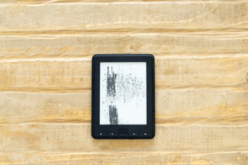 E-book reader with broken screen laying on the wooden table