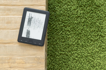 Broken ebook reader laying on the edge of wooden table