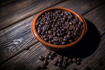The roasted coffee beans lie in a large ceramic plate on a wooden table