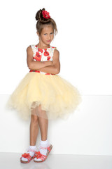 A little girl is looking from behind an empty banner.