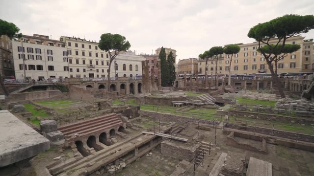 Wide angle view panning across the Largo di Torre Argentina in Rome's city center with no visible people on a cloudy day