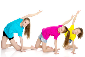 A group of girls gymnasts perform exercises.