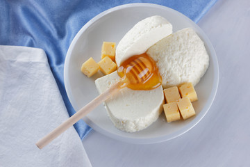 Cheese, milk assortment on white background, white cheese and honey on a blue napkin, wooden...