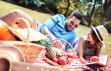 Picnic time. Young couple enjoying picnic in the park. Lifestyle, love, relationships concept - obrazy, fototapety, plakaty