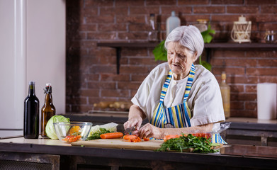 Senior woman chopping fresh vegetables for salad