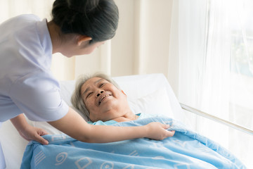 Asian nurse in elderly care cover her with a blanket for the elderly in nursing home.