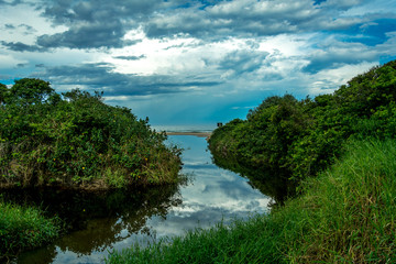 Fototapeta na wymiar Small river mouth near the sea with reflections