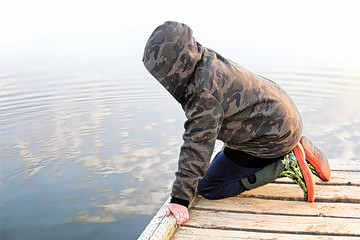 A child looking into water with a mirror reflection of the sky