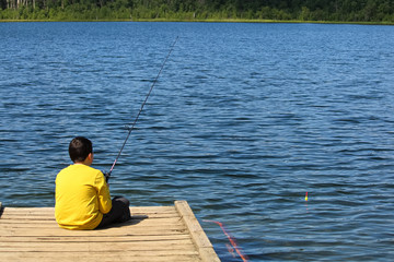 A young boy sitting on a dock and fishing