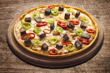 Hot pizza slice with melting cheese on a rustic wooden table.
