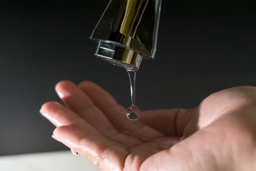 water drop on faucet with  black backgrounds, world water day concept