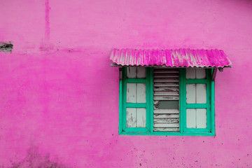 pink building exterior with closed window and wooden shutter