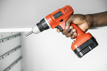 Man using electronic drill install cabinet