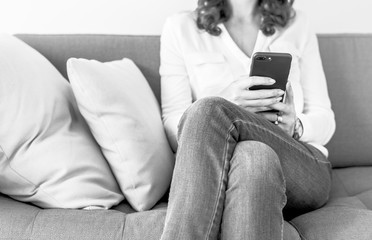 Obraz premium Woman using mobile phone on the sofa