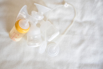 Breast pump equipment and bottle of breast milk for new born baby with white blanket background for text space