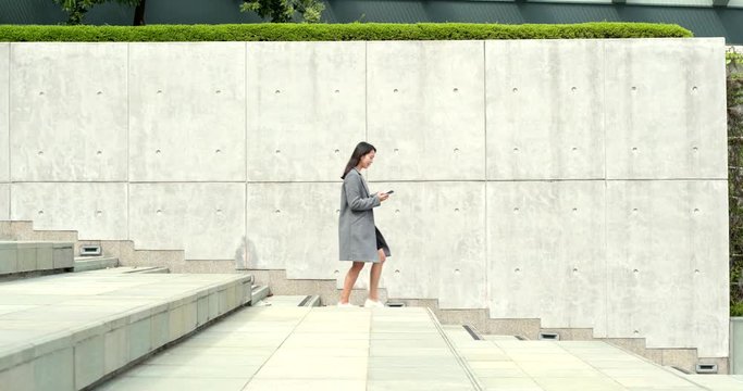 Business woman working on cellphone with walking downstairs at outdoor