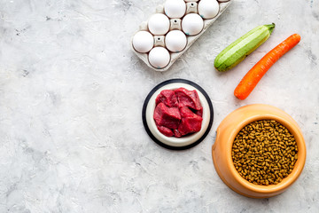 dry organic pet food with fresh vegetables, eggs and meat in plastic bowl for feeding dogs on stone background top view mock up