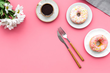 holiday lunch for woman with cup of americano, donut and flowers on pink background top view mock up
