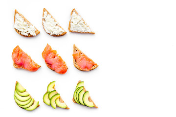 Healthy lunch with mini sandwiches cheese, fish and avocado on white background top view space for text