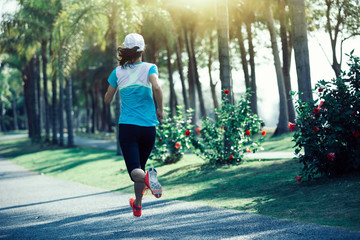 sporty young fitness woman running at tropical park