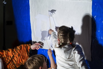 Children play in the shadow theatre. Puppet theatre. Childhood. Tale. - obrazy, fototapety, plakaty