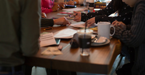 People Playing a Board Game. Gambling. Hands on a Table with Paper Money, Game Pieces, Pencils, Coffee.