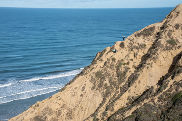 Surfers climb the cliffs up from the beach after catching some waves