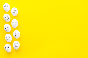 Basic emotions concept. Faces drawn on eggs. Happy, smile, sad, angry, in love. Yellow background top view copy space