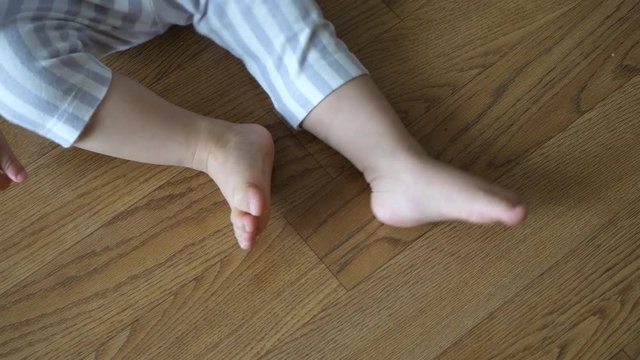 slow-motion movement of leg kicking, behavior of child displease annoy sitting on wood flooring