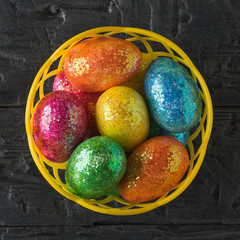 Basket with colorful eggs on a black table. The view from the top.