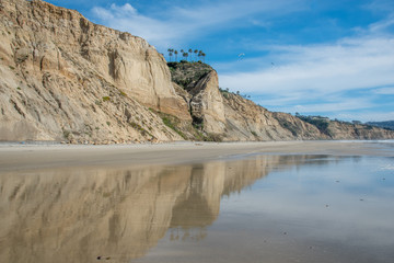 Cliffs at Blacks Beach in San Diego and the beach below Torrey Pines with the coastline reflecting in the wet sand.