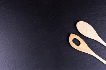 Black slate board for serving with two wooden spoons, top view