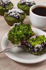 Fresh muffins with spinach, desiccated coconut, chocolate glaze and cup of coffee