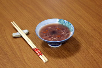 red rice porridge taiwanese style, on wooden table with traditional design chopsticks