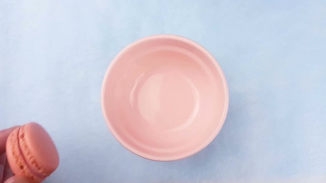 Sweet color macaroons or macaron in pink plate on pastel blue background. Close up.