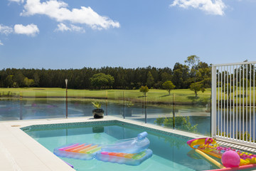 Swimming pool overlooking golf course on a sunny day with blue sky
